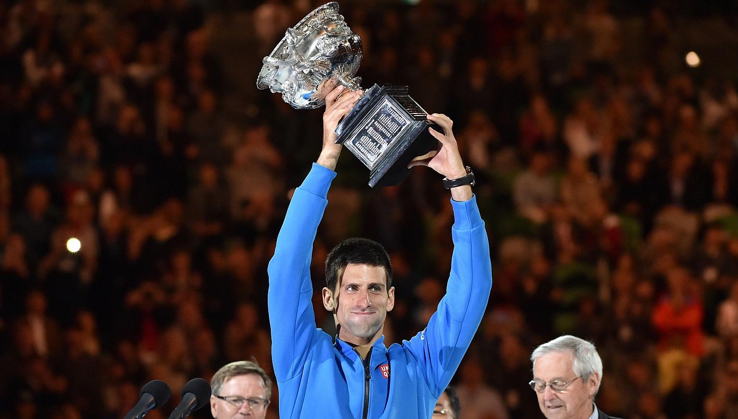 Novak Djokovic of Serbia (centre) holds up the winner's trophy at the awards ceremony as he celebrates his victory over Andy Murray of Britain in their men's singles final match on day 14 of the 2015 Australian Open tennis tournament in Melbourne on