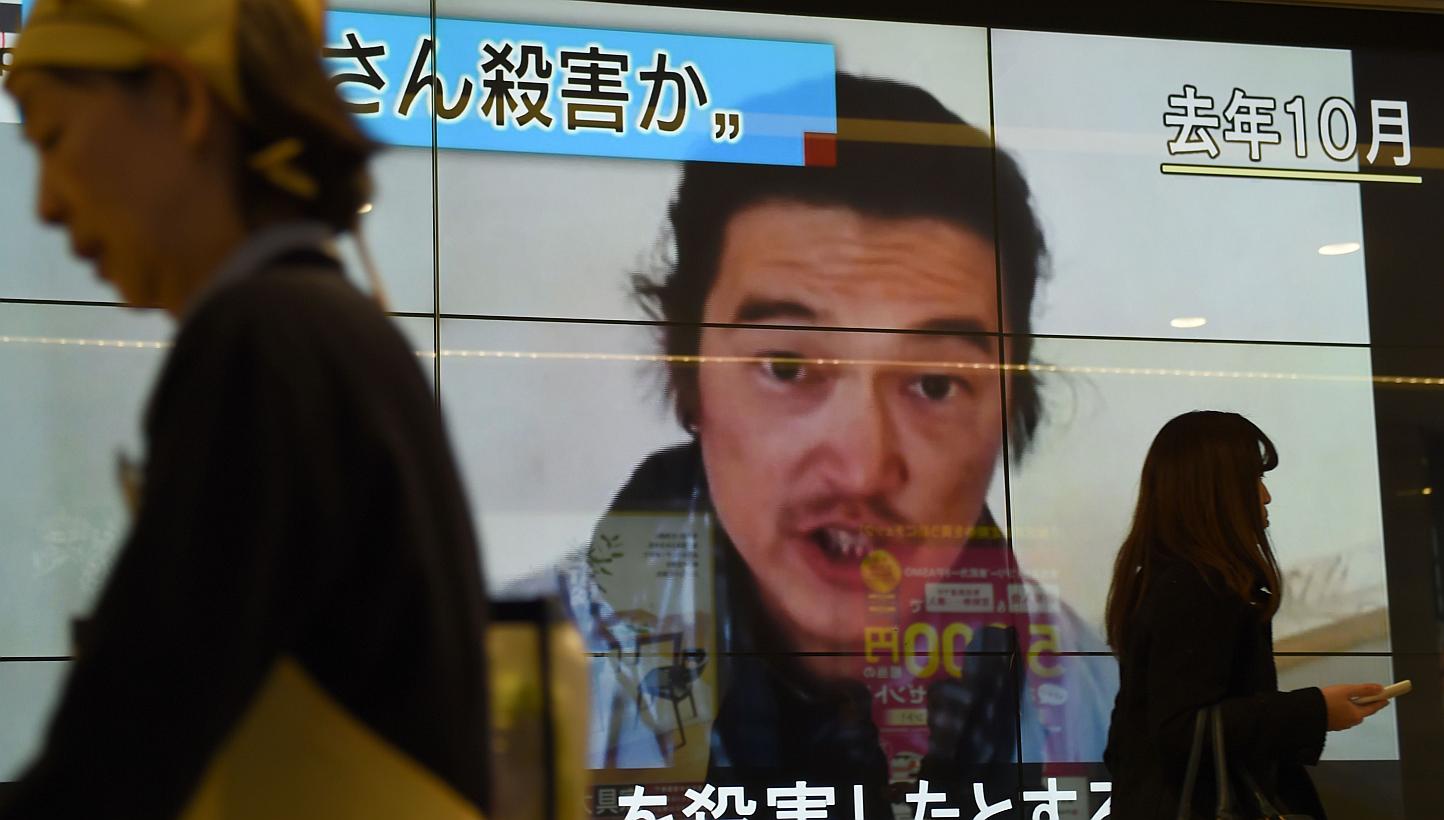 People walk past a big screen reporting that Japanese hostage Kenji Goto was killed by the Islamic State in Tokyo on Feb 1, 2015. -- PHOTO: AFP 