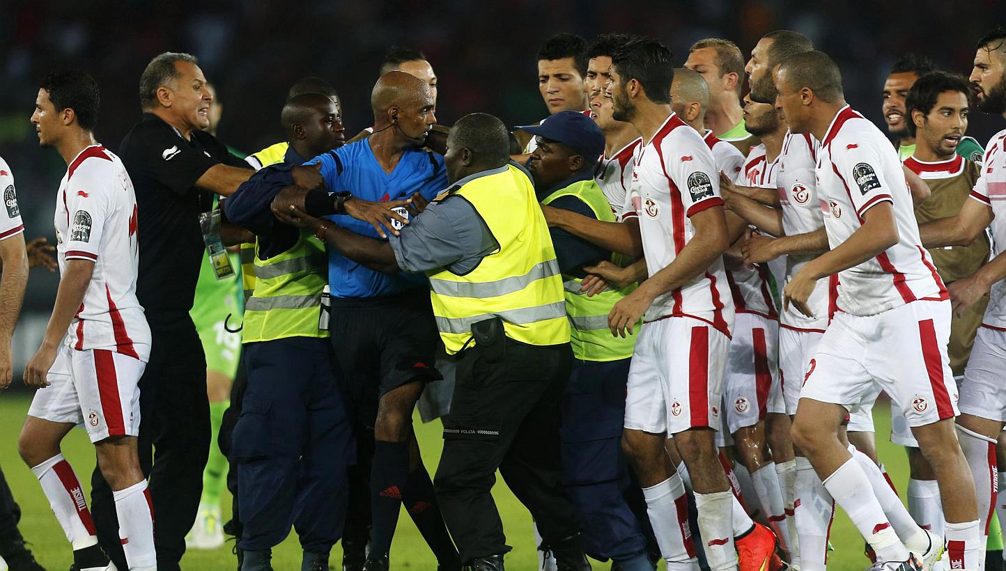 Tunisia players confront referee Seechurn Rajindraparsad (in blue) after losing their quarter-final football match of the 2015 African Cup of Nations against Equatorial Guinea in Bata on&nbsp;Jan 31, 2015. Tunisia are facing heavy punishment after th