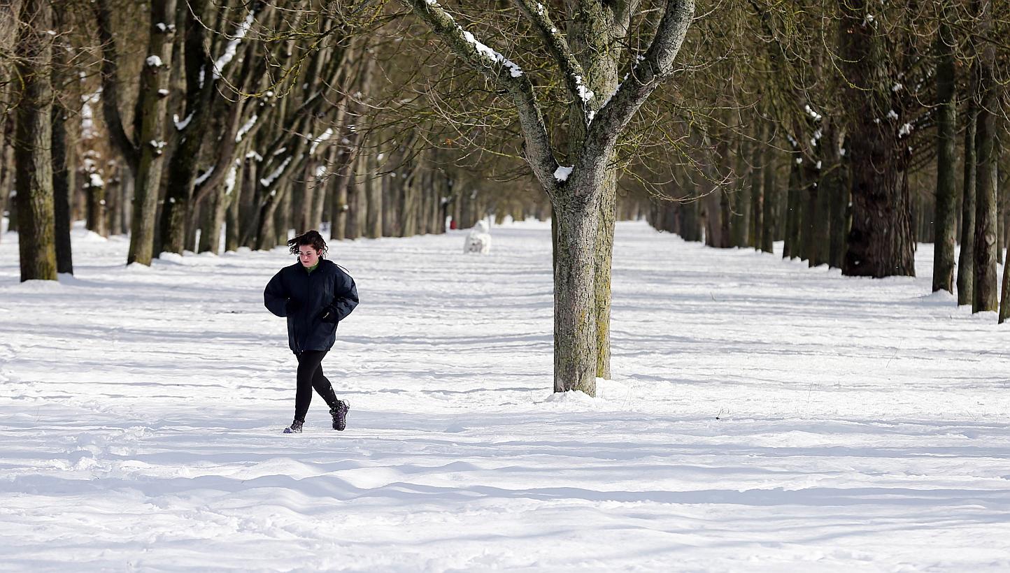 A woman jogs across snow covered la Quinta Park after a heavy snowfall in Burgos, Spain on Sunday. -- PHOTO: AFP 