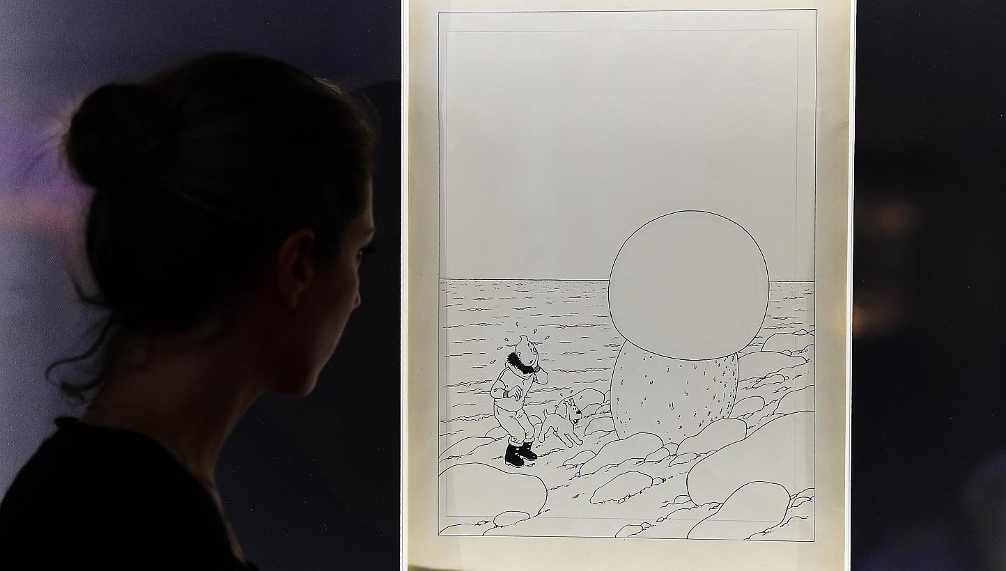 A woman looks at the original artwork to the cover of Tintin et L'etoile Mysterieuse (Tintin And The Shooting Star) by late Belgian cartoonist Herge at the Brussels Antiques and Fine Art Fair, in Brussels. -- PHOTO: AFP