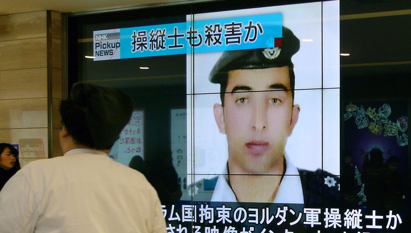 Pedestrians walk past a huge screen reporting on Jordanian pilot Maaz al-Kassasbeh in Tokyo on Feb 4, 2015. -- PHOTO: AFP