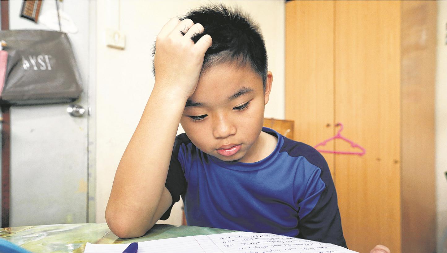 Tay Danzel, 10 trying to concentrate on his homework. More than a third of lower primary school pupils are not getting enough sleep, but only 8 per cent of parents recognise that their child may have sleep problems. -- ST PHOTO: CHEW SENG KIM
