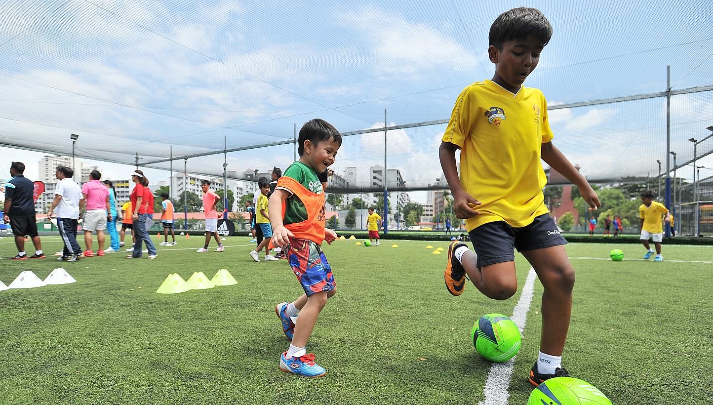 Mohd Rafique Izacq (left), six, and Kumar Arnav, nine, dribbling away at the PAssion Children's Football Family Fiesta 2015 at Home United Youth Football Academy yesterday. The new partnership will allow for football training sessions for children at