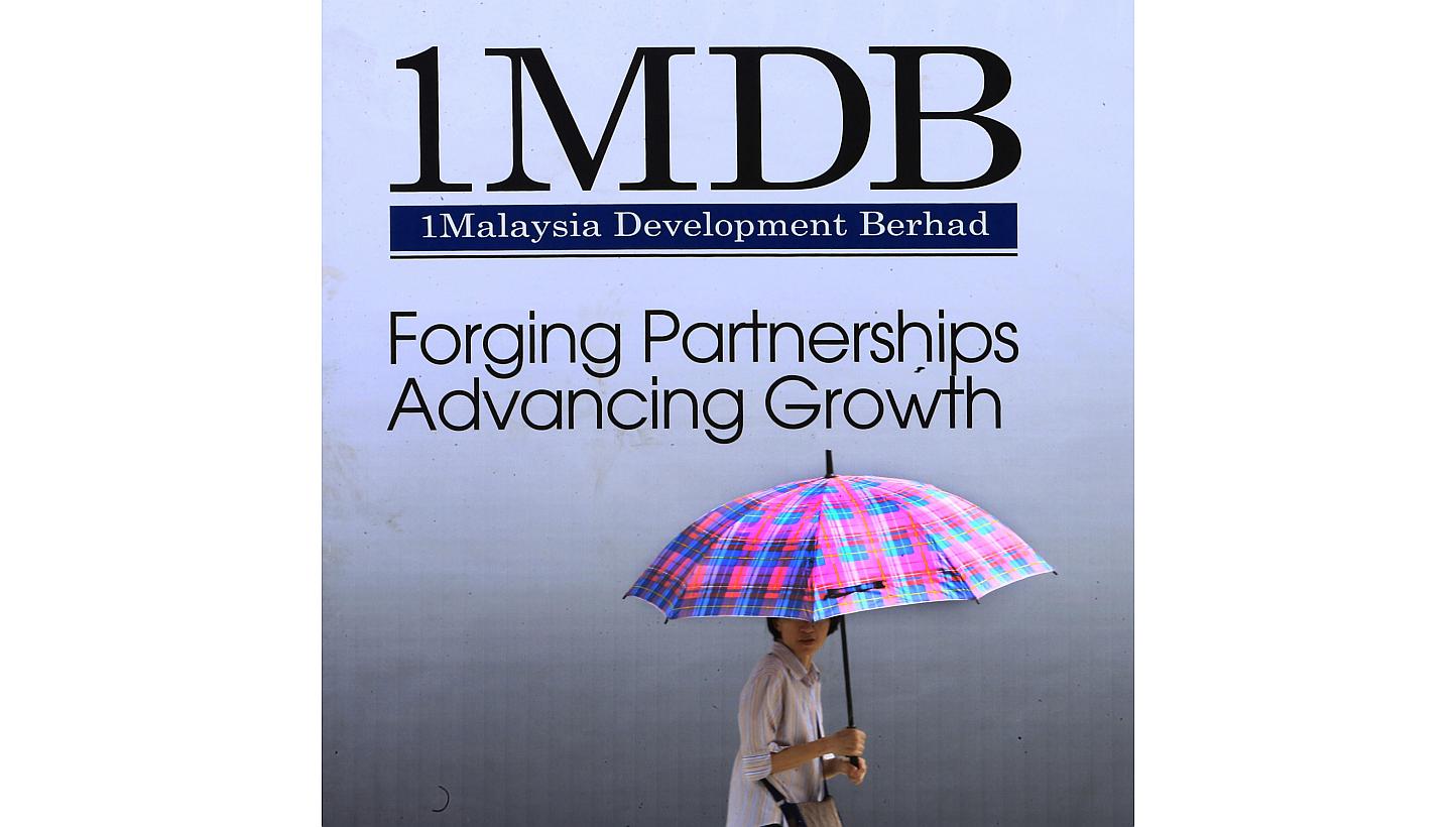 A woman walks past a 1 Malaysia Development Berhad (1MDB) billboard in Kuala Lumpur. Several Malaysian banks could pull the plug on Malaysia's state investment firm 1MDB unless it repays a RM2 billion (S$758 million) loan by the end of this month, re