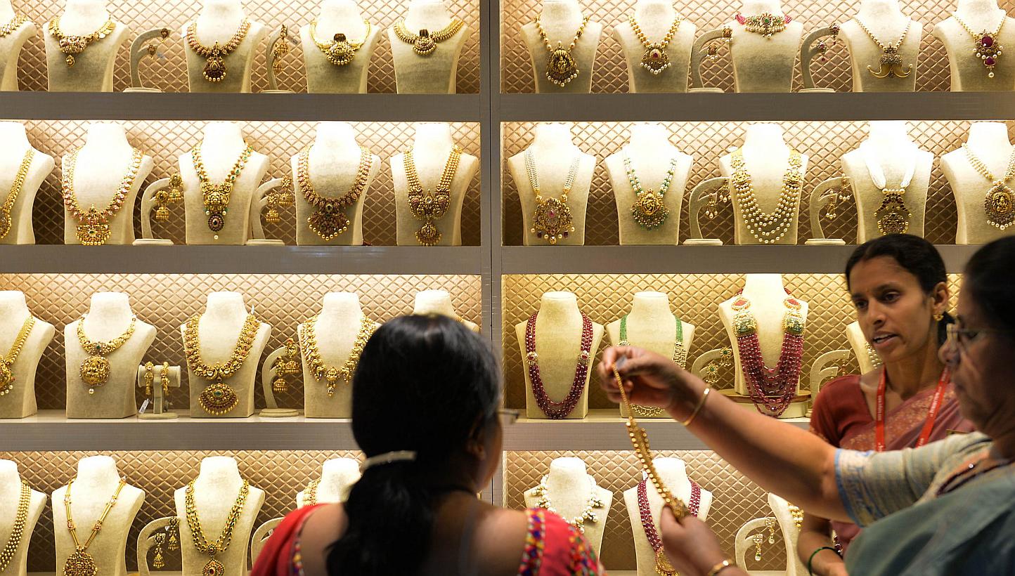 Indian residents examine gold jewellery at a stall during the 'Asia Wedding Fair 2015' in Bangalore on Feb 6, 2015. Gold demand fell for a third year on a slump in purchases from China, costing the country its place as the world's biggest buyer to In