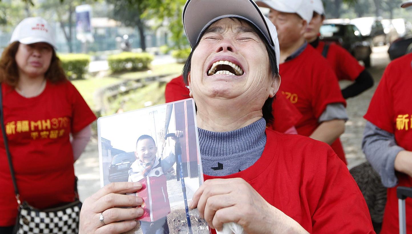 The mother of a passenger of missing Malaysia Airlines Flight MH370 holding a picture of her grandson outside the Malaysia Airlines headquarters in Kuala Lumpur on Feb 12, 2015. -- PHOTO: REUTERS