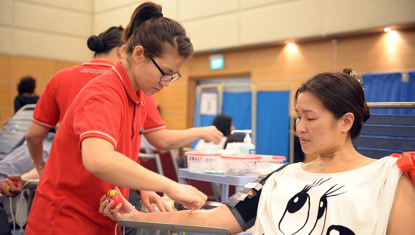 Miss Deslyn Lee, 44, a SPH staff from Classified, is donating her blood for the 11th time with SPH Blood Donation Drive with the help of Blood Bank nurse, Miss Ho Xin Xia, Avelina, 28. -- ST PHOTO: DANIEL NEO