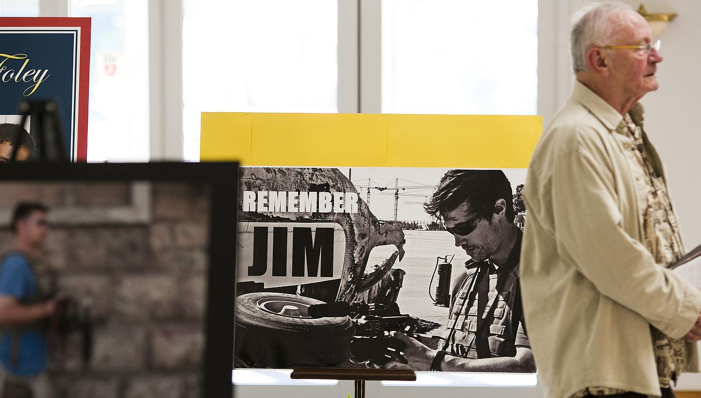A file photo taken on Aug 24, 2014 shows a parishioner walking past a display of photos of murdered US journalist James Foley before a Catholic mass at Our Lady of the Holy Rosary Parish in Rochester, New Hampshire. -- PHOTO: AFP