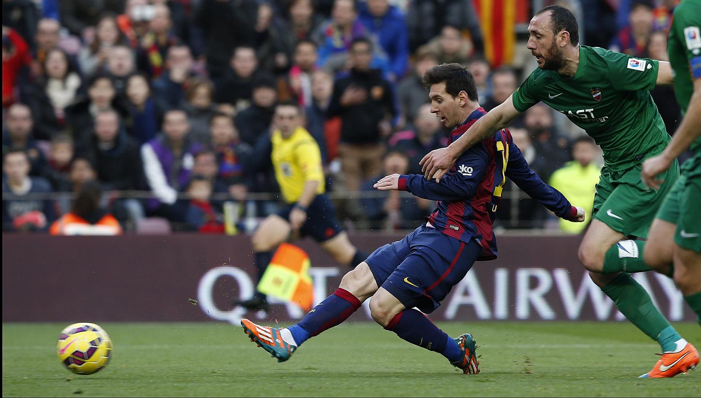 Barcelona's Lionel Messi (L) shoots to score a goal beside Levante's Ivan Ramis during their Spanish first division soccer match at Nou Camp stadium in Barcelona on Sunday. -- PHOTO: REUTERS