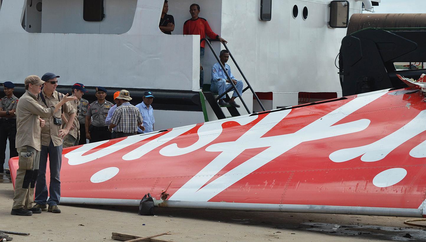 Foreign investigators (left) examining the tail of the AirAsia flight QZ8501 in Kumai on Jan 12, 2015, after debris from the crash was retrieved from the Java Sea. Indonesia will release the final report onlast year's AirAsia plane crash by Aug