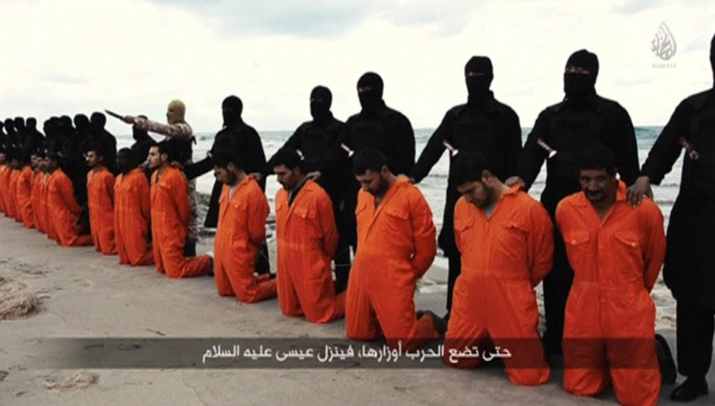 Men in orange jumpsuits purported to be Egyptian Christians held captive by the Islamic State in Iraq and Syria (ISIS) kneel in front of armed men along a beach said to be near Tripoli, in this still image from an undated video made available on soci