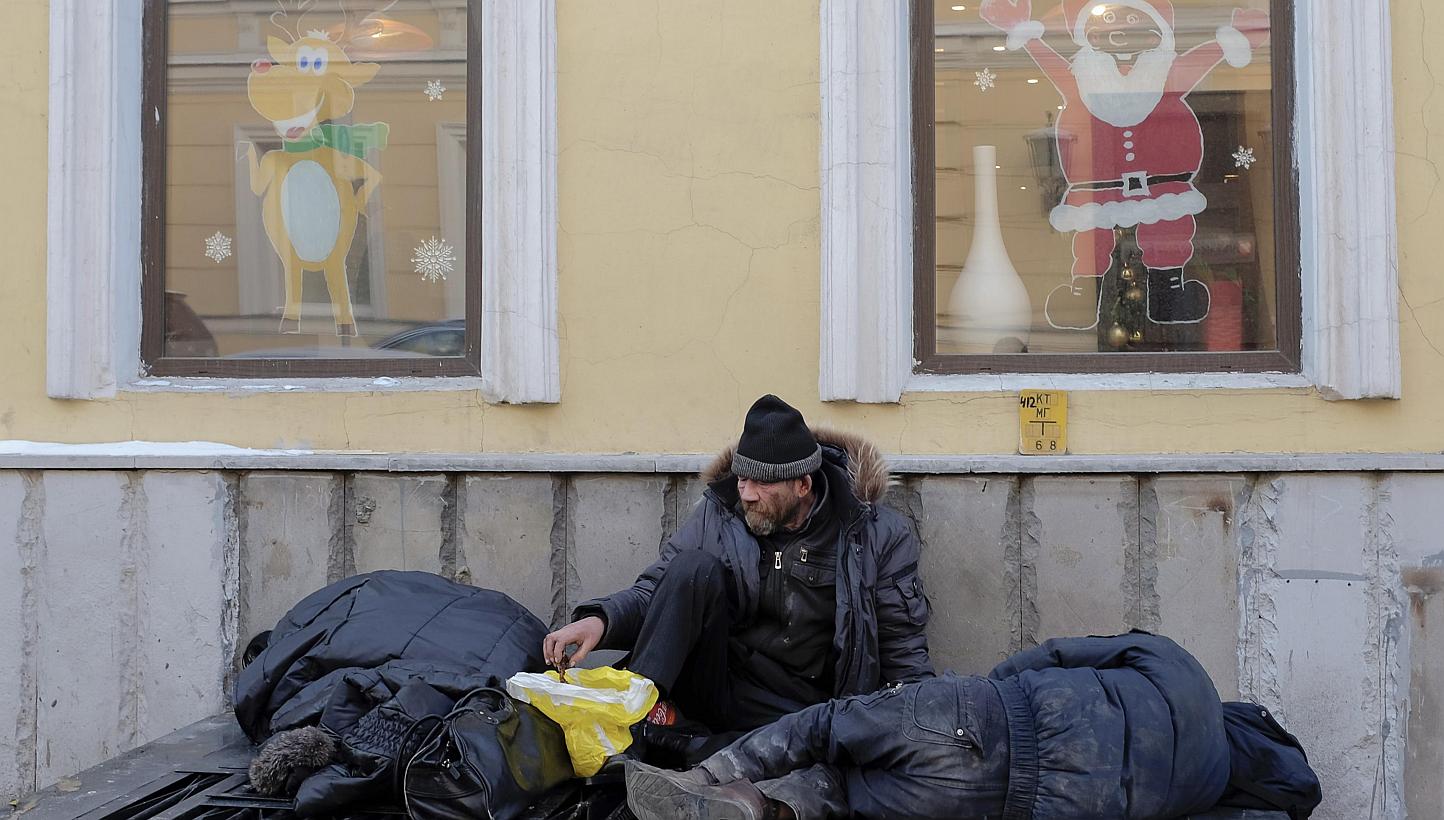 Homeless men warm themselves on a ventilation outlet under windows with festive decorations in Moscow on Dec 30, 2014.&nbsp;A Russian couple allegedly carried out a string of murders targeting homeless people in Moscow to "clean up" the city, investi