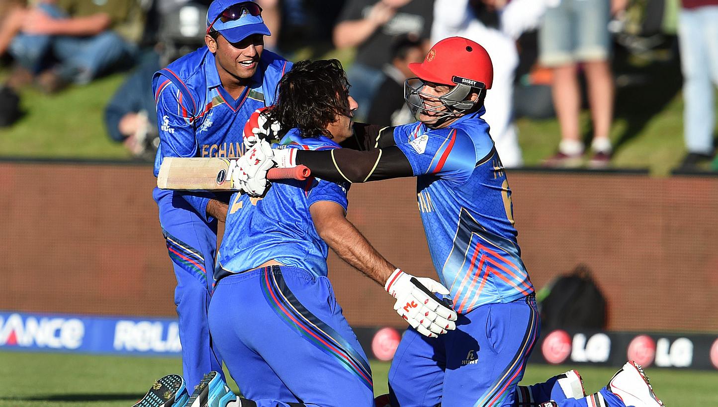 Afghanistan batsman Shapoor Zadran (centre) celebrates with teammate Hamid Hassan (right) after hitting the winning runs to defeat Scotland as reserve Usman Ghani (left) looks on in their 2015 Cricket World Cup Group A match in Dunedin on Feb 26, 201