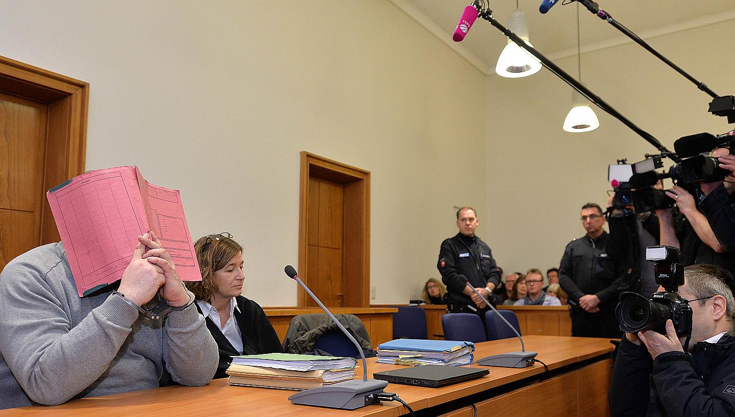 German hospital nurse Niels H (left) hides his face behind a folder as he waits next to his lawyer Ulrike Baumann (second, left) for the opening of another session of his trial on Feb 26, 2015, at court in Oldenburg, north-western Germany. -- PH