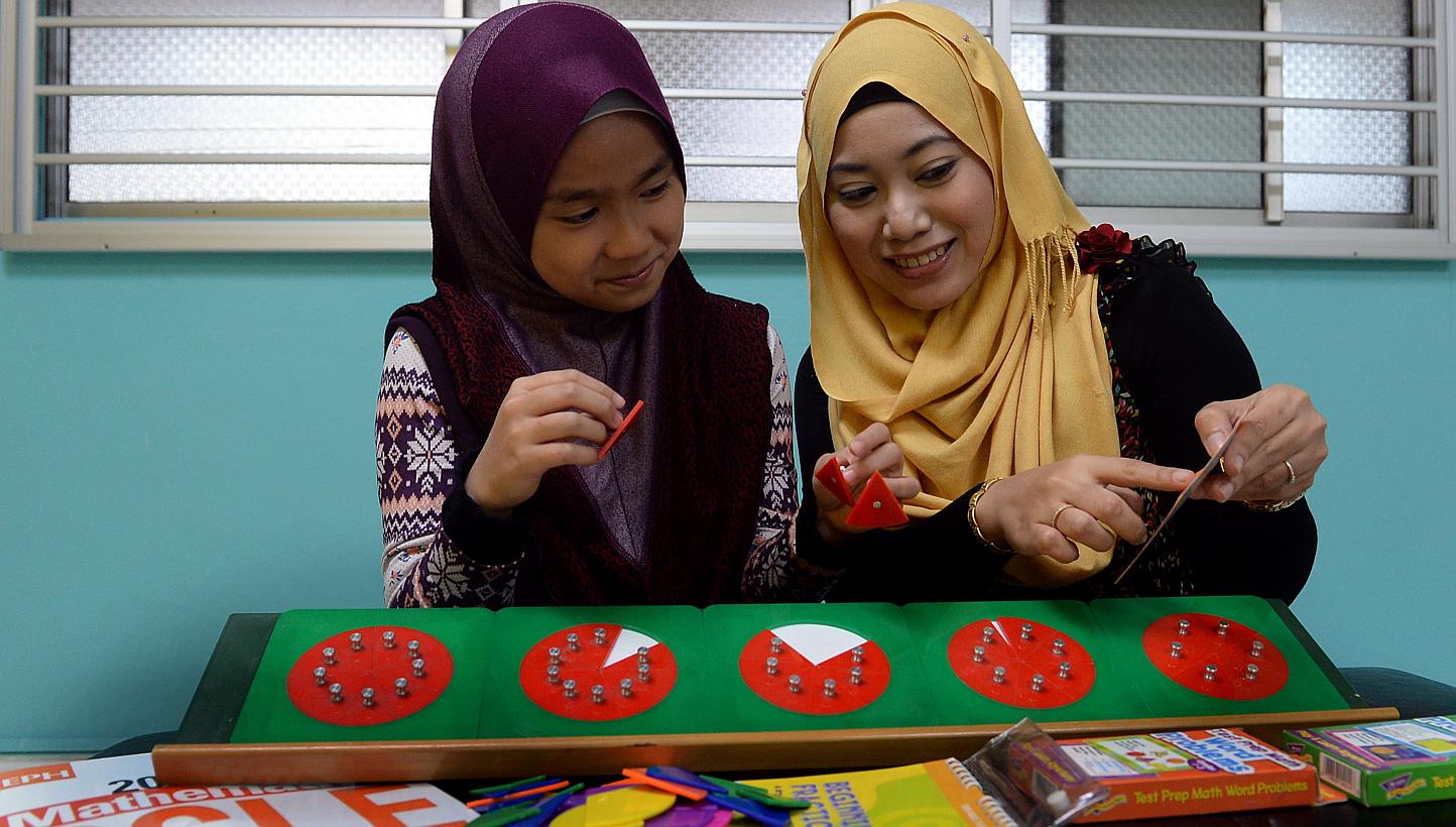 Ms Nurhidayah Mohamad Ismail (right), principal of Genius Young Minds, showing Naily Afiqah Zailanio, a student from Irsyad Zuhri Madrasah, how to use the 'fraction board' so that she can see and understand the concept of fractions better. -- BH PHOT