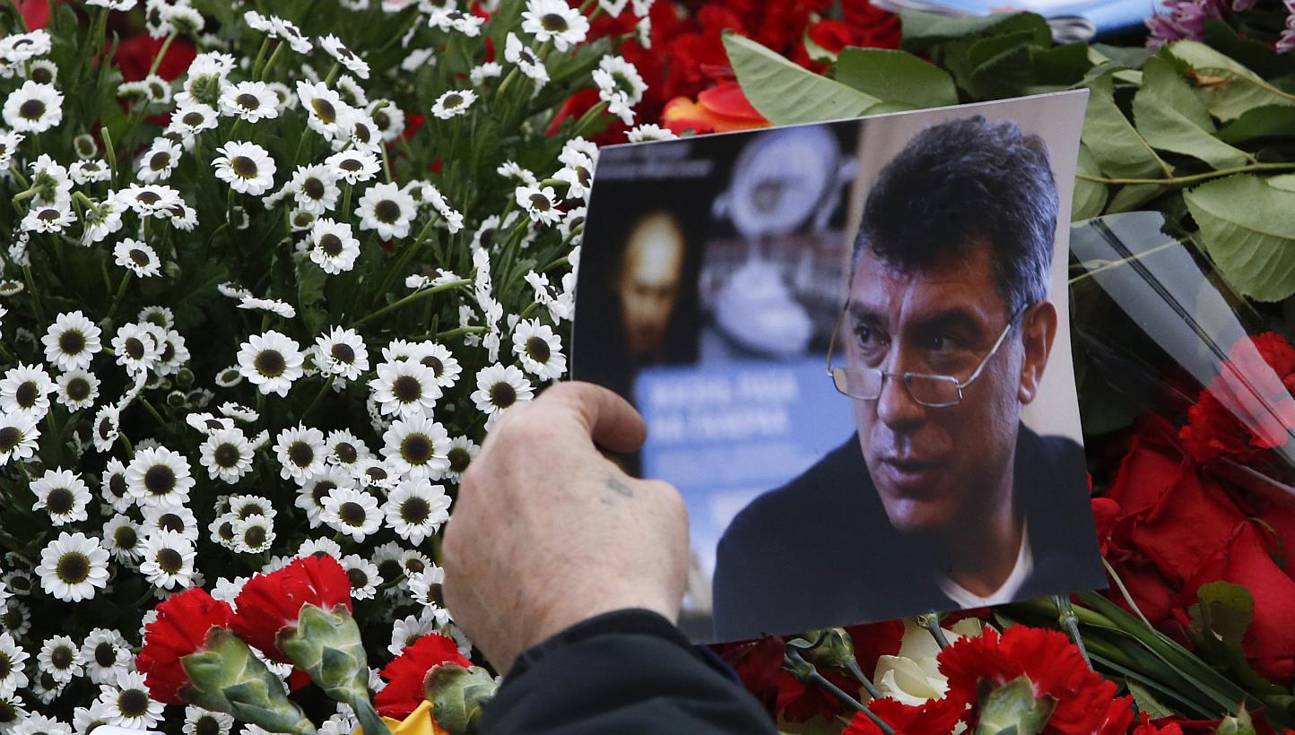 A visitor holds a photo at the site where Boris Nemtsov was recently murdered, in central Moscow, Feb 28, 2015. Nemtsov had enemies politically and personally. Even among the opposition, his outsized character pulled some into his orbit and push
