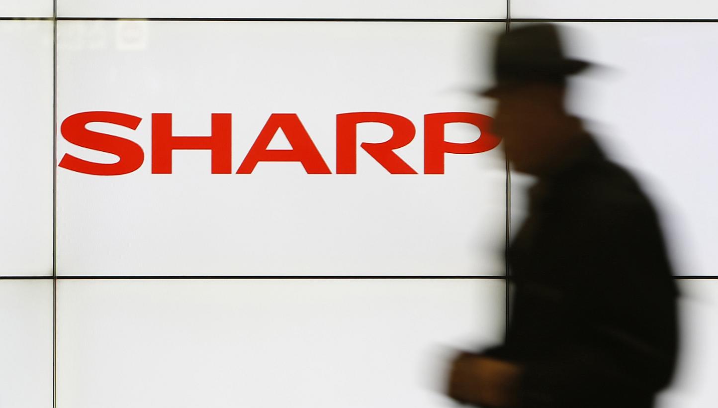 A pedestrian walks past a logo of Sharp Corp at a train station in Tokyo in this Feb 3, 2014 file photo. The company's shares tumbled nearly 10 per cent in early trade on Tuesday after the Nikkei business daily reported that the struggling electronic