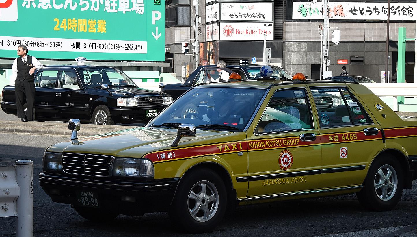 Taxi drivers wait for passengers in front of a railway station in Tokyo. Japan has slammed the brakes on a pilot project by taxi service Uber less than a month after it was launched. -- PHOTO: AFP