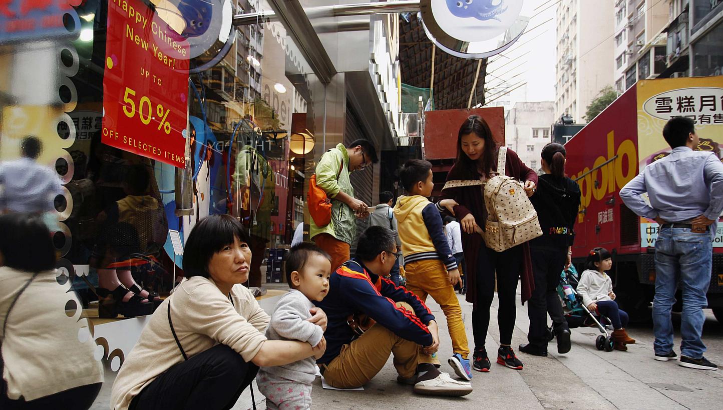 Tourists from mainland China resting outside a shop at a shopping district in Hong Kong on Feb 24, 2015. -- PHOTO: REUTERS&nbsp;