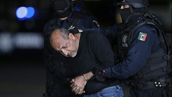 Former primary school teacher Servando "La Tuta" Gomez is escorted by police officers during a media conference about his arrest in Mexico City last week. Mexico captured its most wanted drug lord on Friday, delivering a boost to a government battere