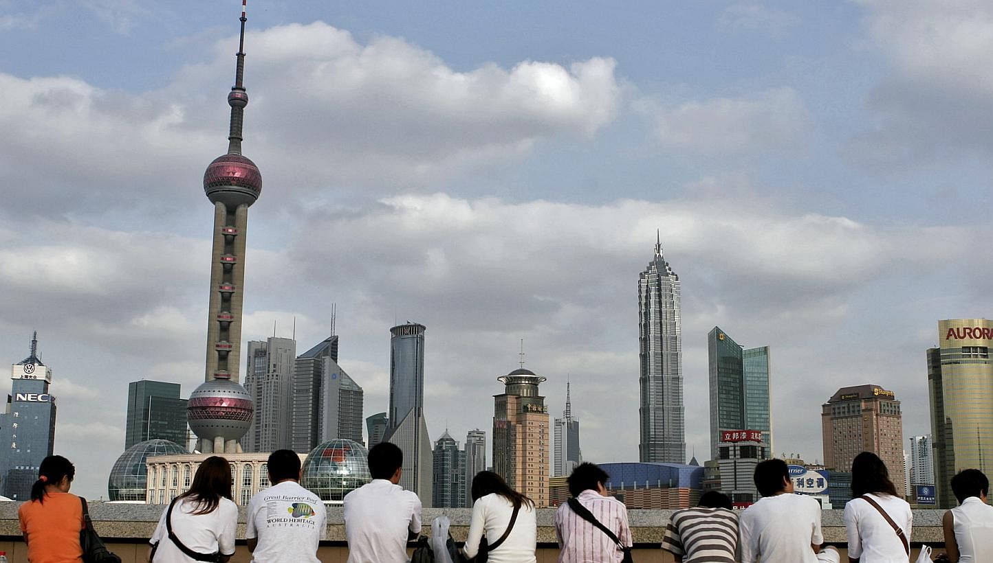 Visitors gather on Shanghai's famous Bund to look at the skyline of the Pudong financial district across the Huangpu River. China has lowered its 2015 economic growth target to "around 7 per cent", state media said on Thursday, as the authorities att