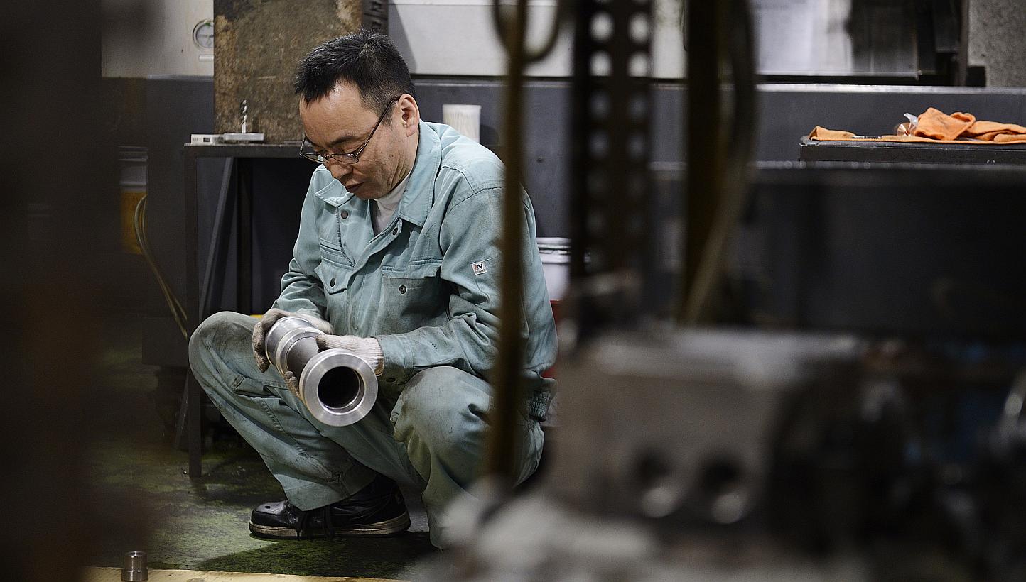 An employee inspecting a machined component at a Kyokuto Seiki Seisakusho K.K. metal machining factory in the Ota ward of Tokyo, Japan, on Dec 5, 2014. -- PHOTO: BLOOMBERG 