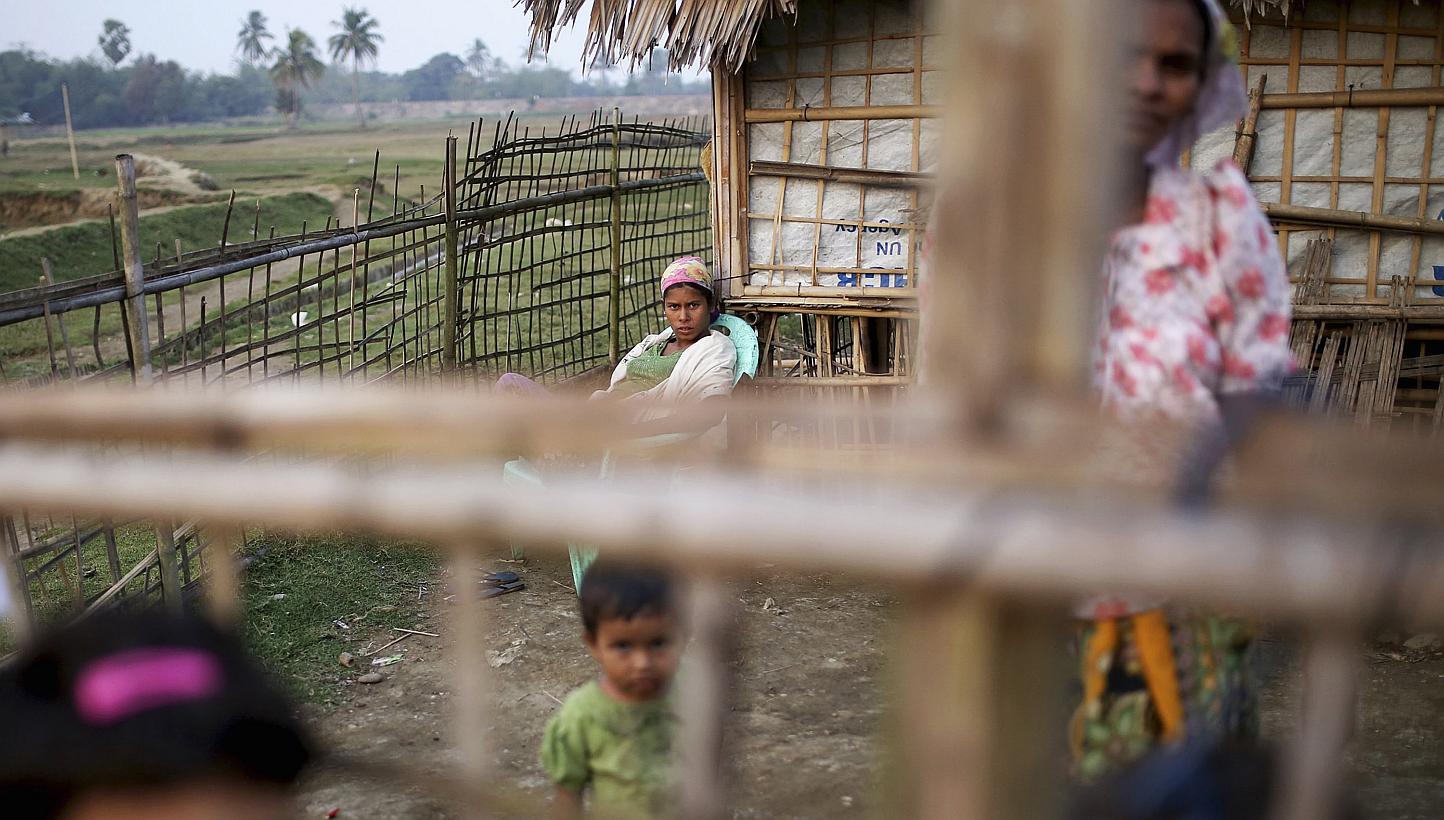 Internally displaced Rohingya women and children look from behind the fence of their temporary home at Thae Chaung IDP camp on the outskirts of Sittwe on Feb 15, 2015.&nbsp;Myanmar authorities have begun collecting temporary identification cards from