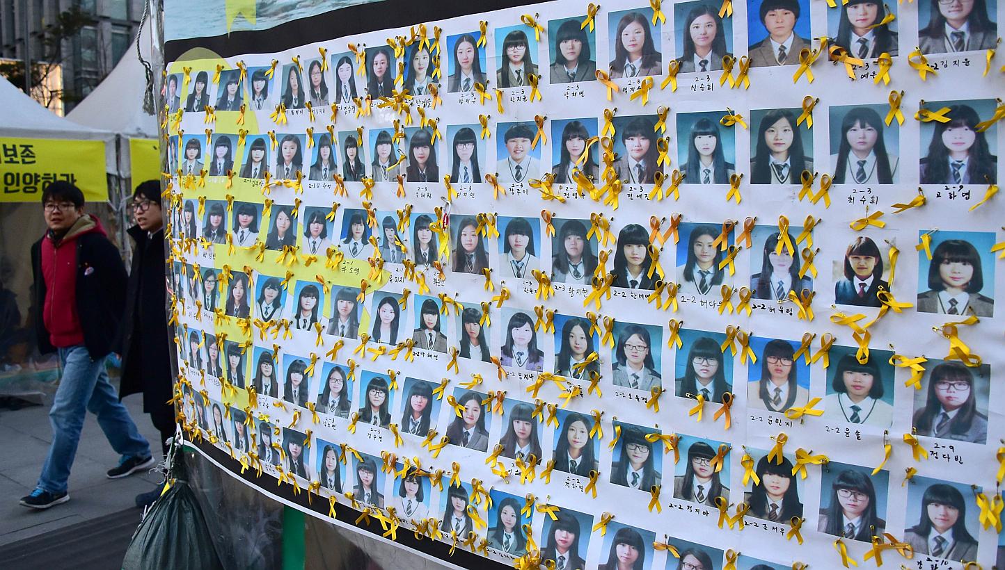 Pedestrians walk past portraits of the victims of the sunken South Korean ferry "Sewol" at Gwanghwamun square where relatives of the victims have been sitting in protest against the government, in Seoul on Jan 8, 2015. -- PHOTO: AFP