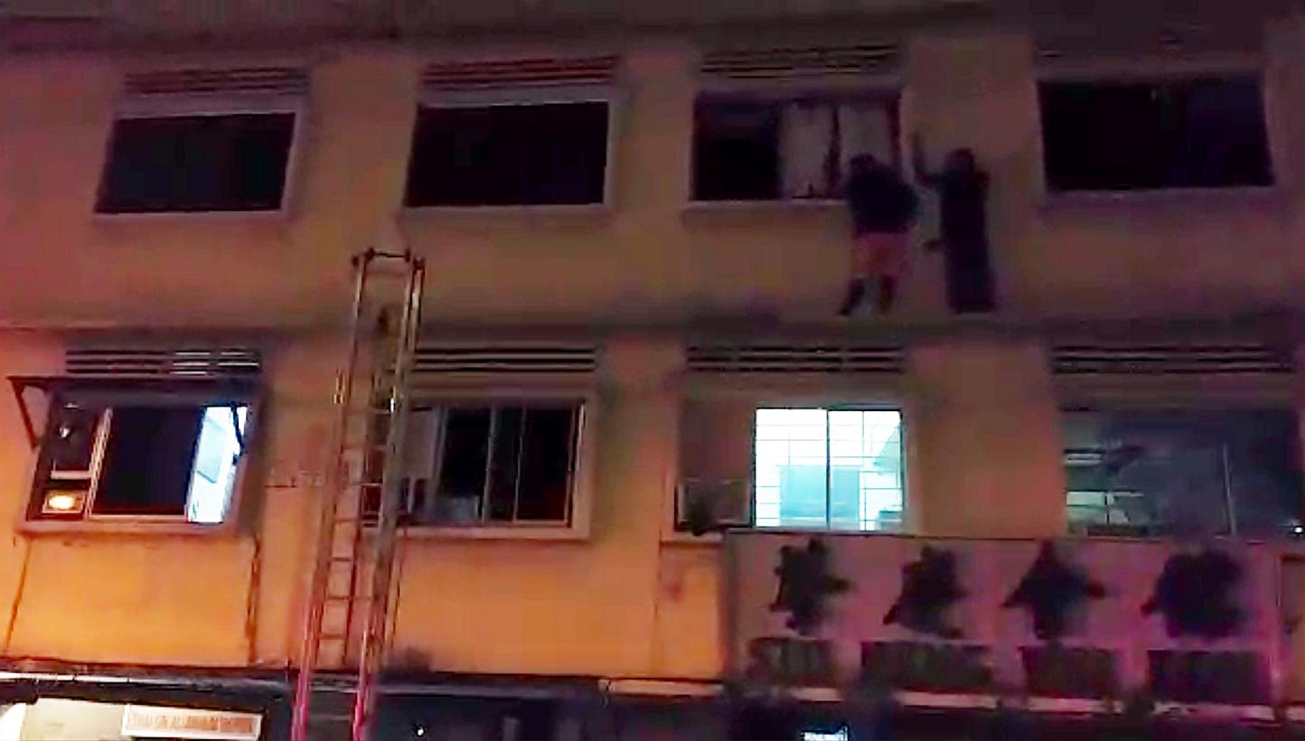 Two foreign workers who went out on the ledge on the third floor of the apartment in 35 Geylang Lorong 4 on December 7,2014, trying to get to safety from the fire that broke out on the ground floor. Four foreign workers died in the fire. -- PHOTO: SH