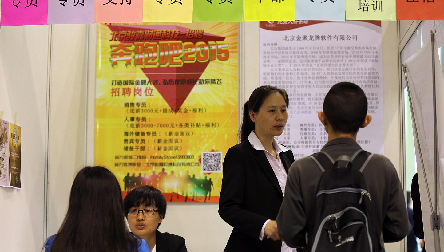 Job seekers speaking with representatives at a job fair for Beijing-Tianjin-Hebei province enterprises in Beijing, China on April 29, 2015. -- PHOTO: EPA