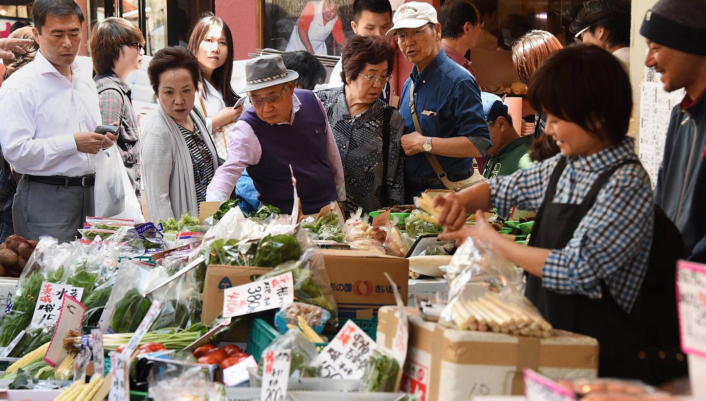 Shoppers choosing vegetables at a fruit and vegetable store in Tokyo on May 1, 2015. -- PHOTO: AFP&nbsp;