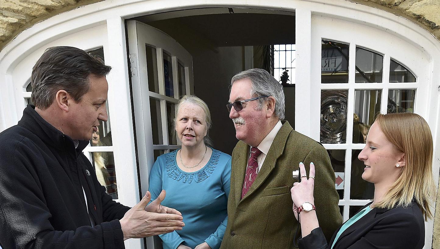 Britain's Prime Minister David Cameron (left) speaks with locals during a 'walkabout' whilst campaigning in Wetherby in northern England, Britain, April 30, 2015. A feisty audience grilled Britain's political leaders on Thursday over what deals and c