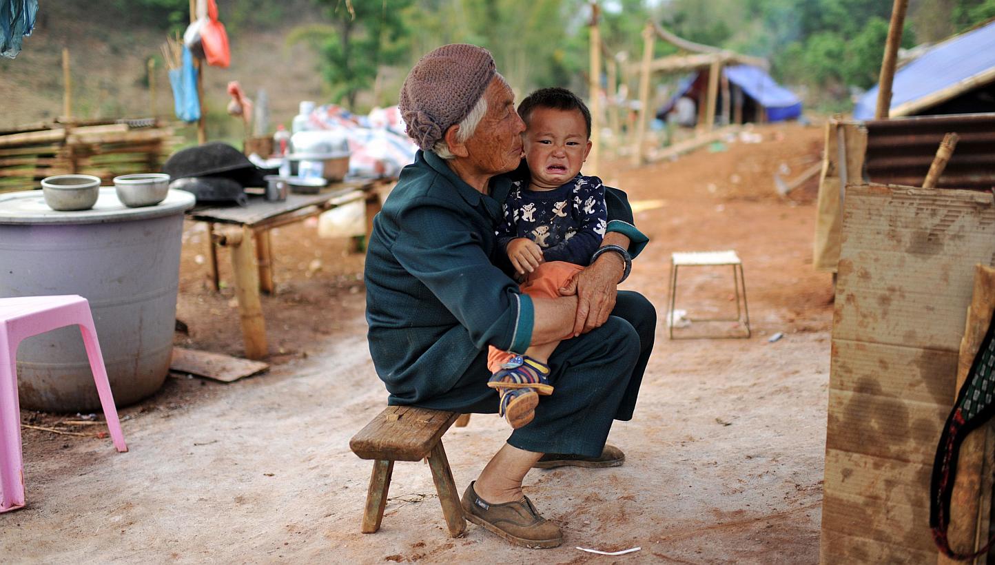 This picture taken on April 6, 2015, shows a Kokang refugee holding a child in her arms at a temporary shelter in the border area of China and Myanmar in Nansan township in Lincang, southwest China's Yunnan province. Tens of thousands of refugees hav