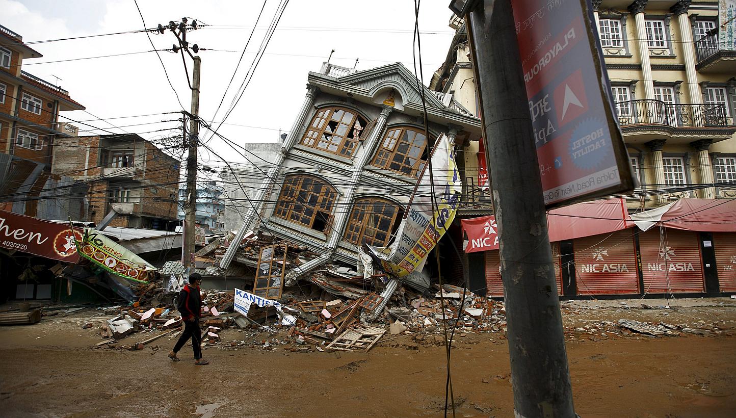 A man walks along the street near a collapsed house following Saturday's earthquake in Kathmandu, Nepal May 1, 2015. US military aircraft, heavy equipment and air traffic controllers will start arriving in Nepal from Saturday as part of a US relief o