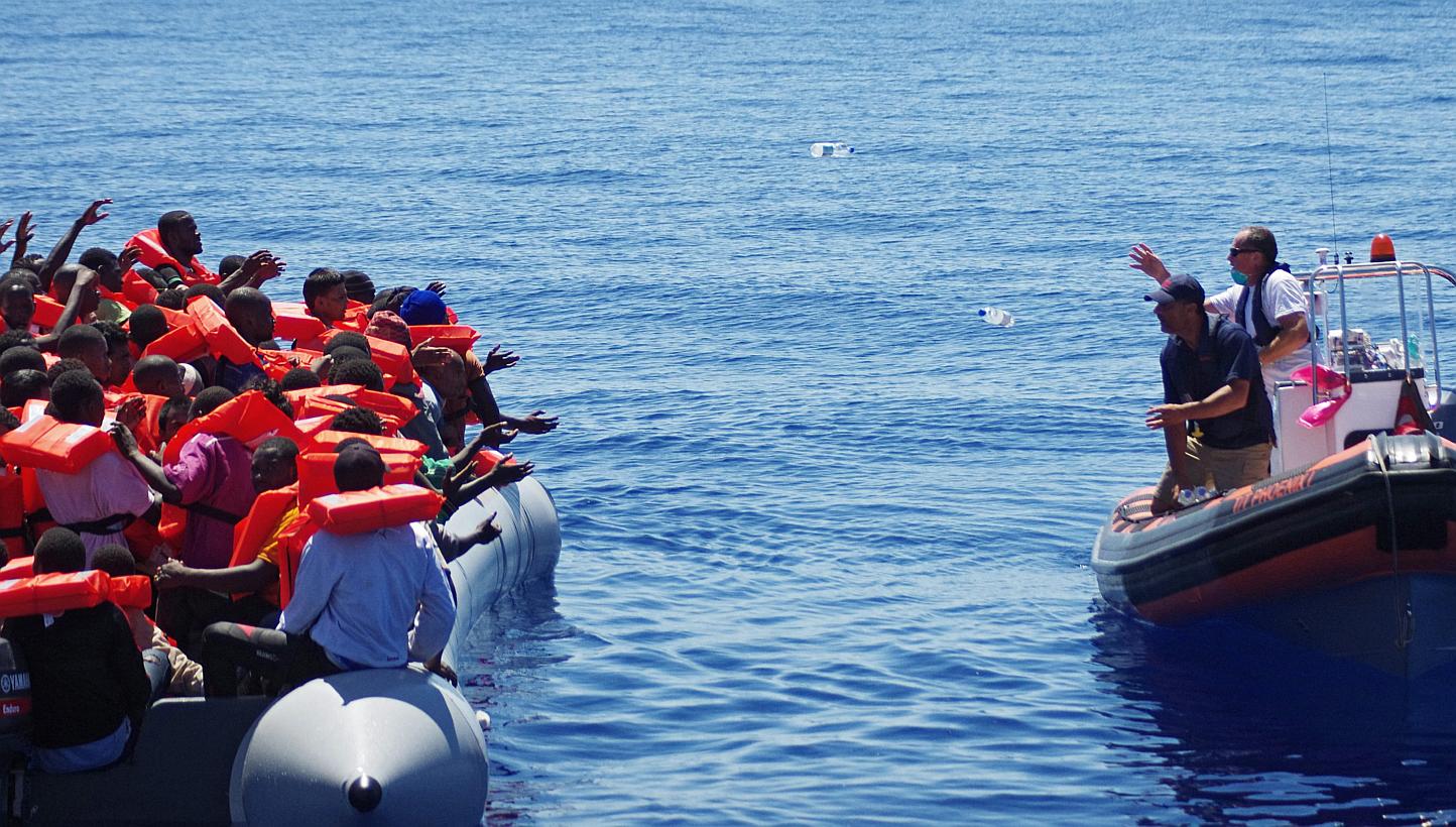 A handout picture made available on May 2, 2015 of Migrant Offshore Aid Station (MOAS) employees throwing bottles of water from a dinghy of the ship 'Phoenix' to refugees in a rubber raft off Malta, on August 30, 2014. -- PHOTO: EPA&nbsp;