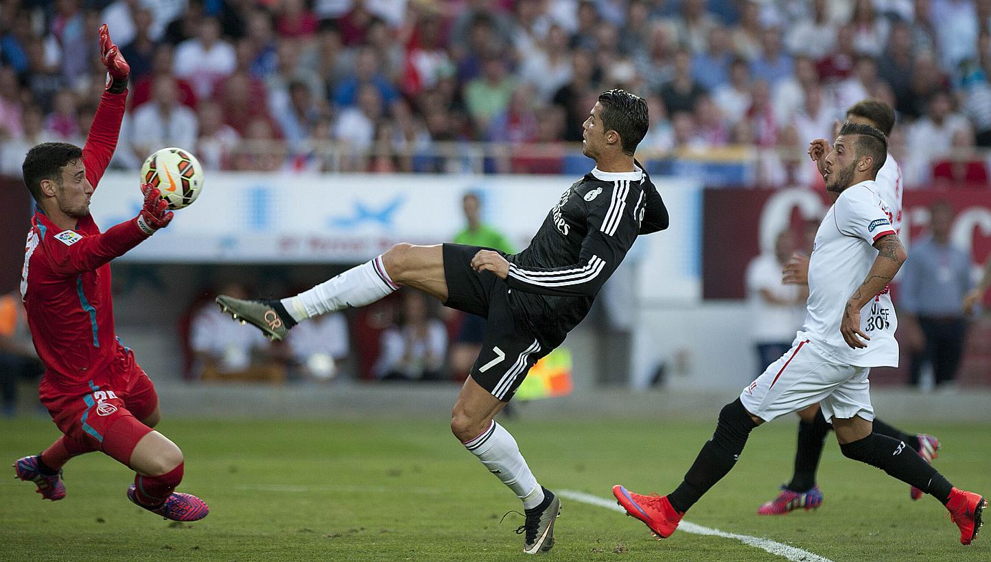 Real Madrid's Cristiano Ronaldo (centre) scores past Sevilla's goalkeeper Sergio Rico (left) on May 2, 2015. -- PHOTO: AFP&nbsp;