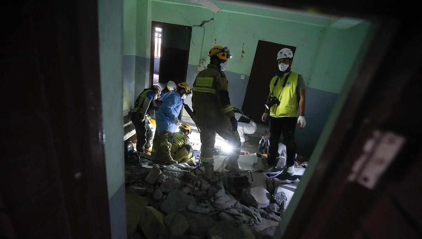 Members of Korea's Human in Love search and rescue team together with a team from Oman cut the floor of a room in a fallen building as they try to free the body of a woman, in Balaju, Kathmandu, Nepal, May 3, 2015. Nepal has asked foreign countr