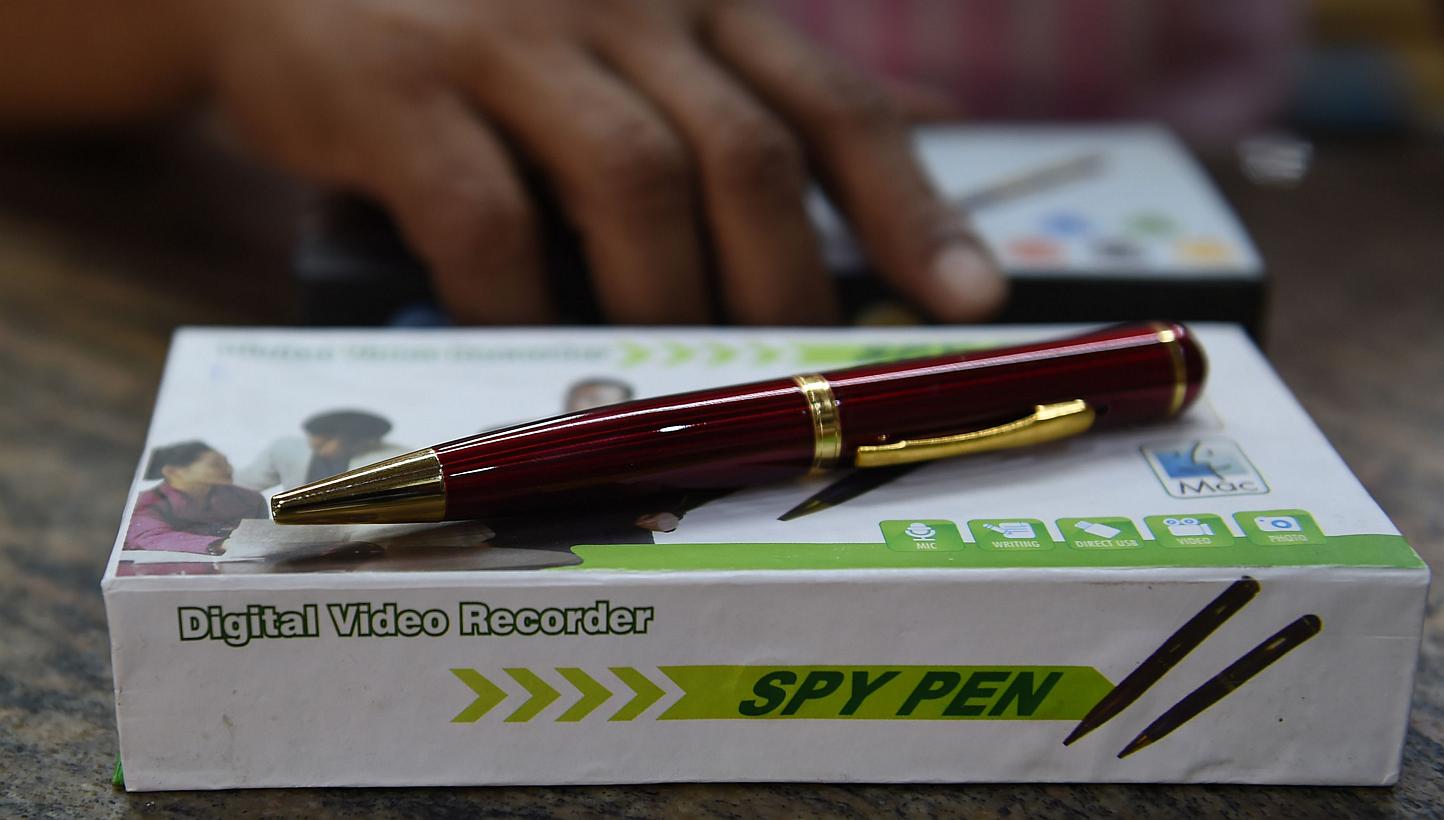 In this photograph taken on April 17, 2015, an Indian shopkeeper presents a 'spy pen' - a pen with a camera fitted - at a store in New Delhi. Tiny bluetooth earpieces, "spy bras" and hidden camera glasses: these are just some of the high-tech gadgets