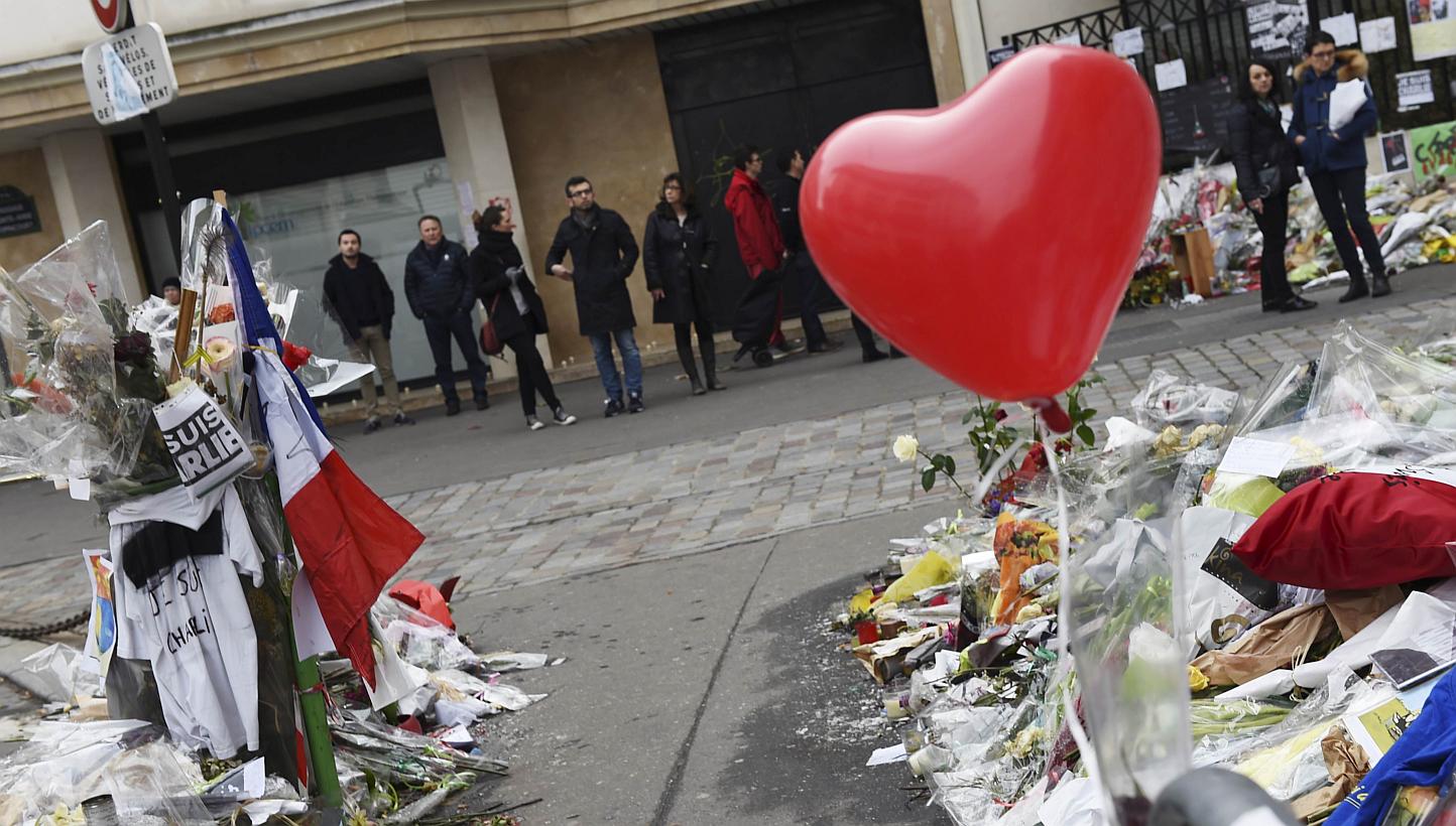 People paying homage outside the headquarters of French satirical weekly Charlie Hebdo in Paris on Feb 15, 2015. -- PHOTO: AFP