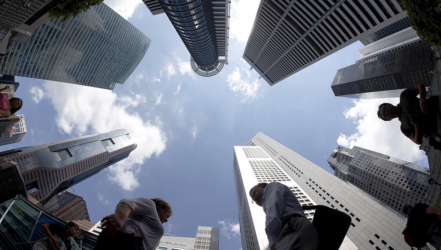 People walk past office buildings at the central business district in Singapore in this April 14, 2015 file photograph. The tough times show no sign of letting up for manufacturers in Singapore and across Asia going by dismal PMI numbers out on Monda