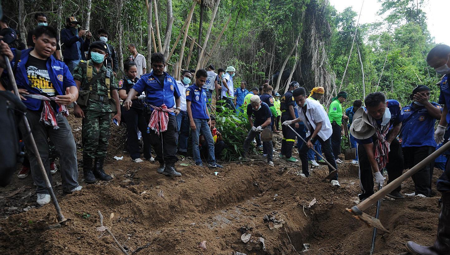 Rescue workers and forensic officials digging out skeletons from a mass grave at an abandoned jungle camp in the Sadao district of Thailand's southern Songkhla province on May 2, 2015. Investigators in southern Thailand have discovered five graves at