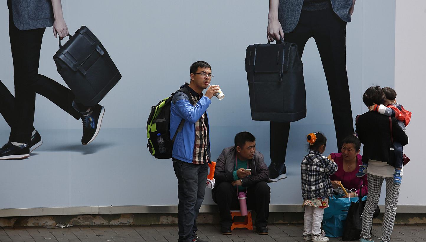 Visiting mainland Chinese families rest under an advertisement board at a shopping district in Hong Kong on Feb 23, 2015. A female tour guide in Yunnan who castigated her tour group for not shopping enough was sacked, after a video of her scoldi