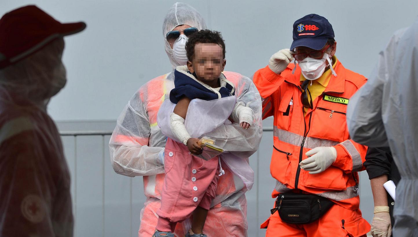 Officials assist a refugee child after they disembark from the Italian Navy vessel 'Bettica' in the harbor of Salerno, Italy, on May 5, 2015. On Monday more than 3,000 migrants landed in southern Italian ports on board the Italian navy patrol ship Be