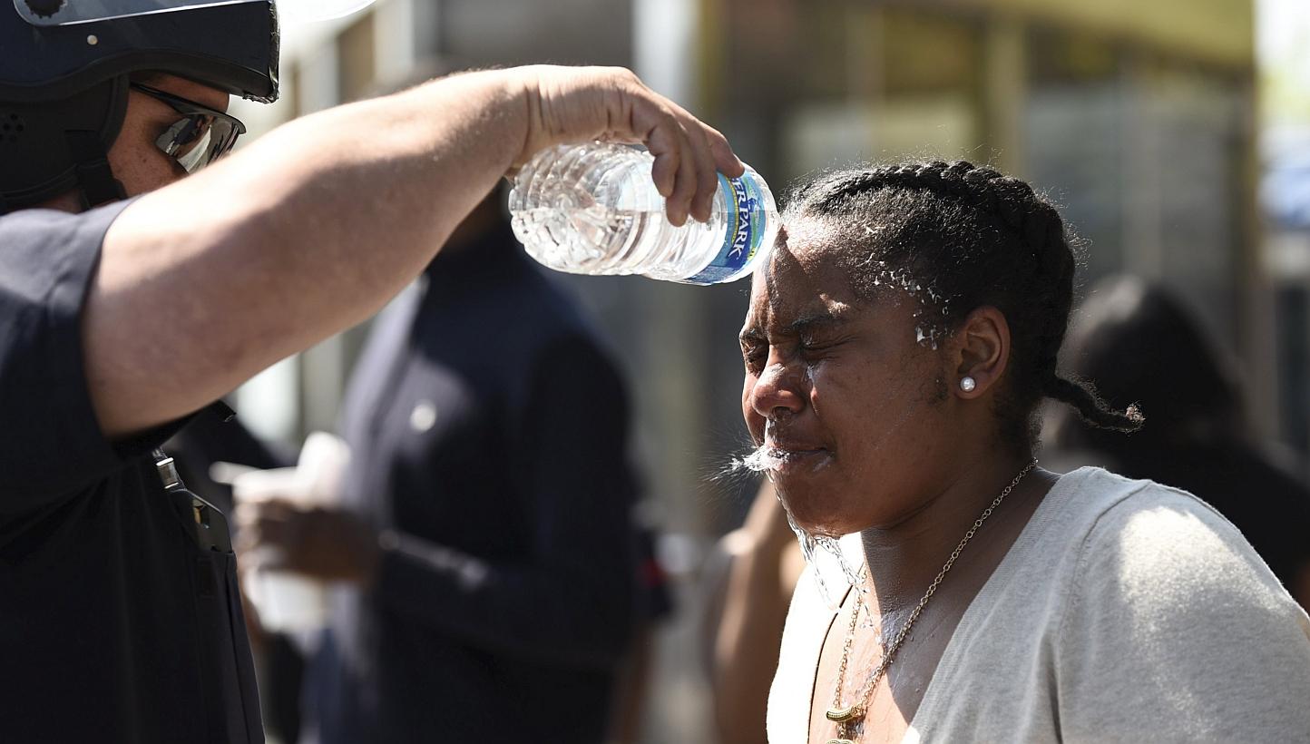 A law enforcement officer washes the face of a woman who was affected by pepper spray in Baltimore, as protests threatened to arrest again after a false shooting report. -- PHOTO: REUTERS