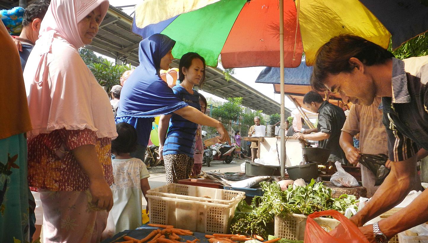 Women purchasing food from street vendors at a traditional market in Jakarta on March 19, 2015. -- PHOTO: AFP