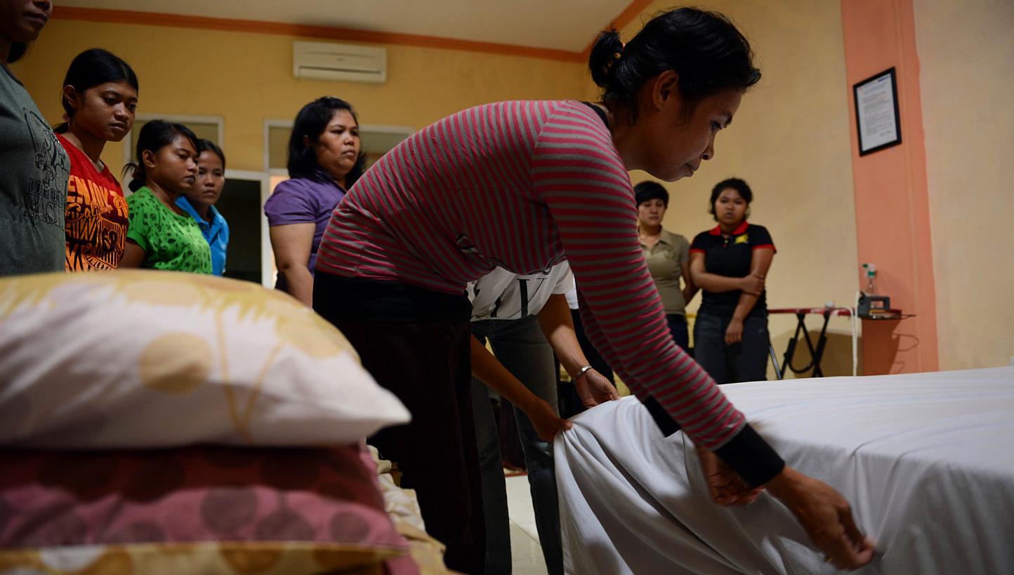 In this file photograph taken on January 27, 2014, an Indonesian maid learns to fix a bed in Jakarta during a class for a group of maids undergoing training at a private recruitment agency deploying maids to foreign countries. -- PHOTO: AFP&nbsp;