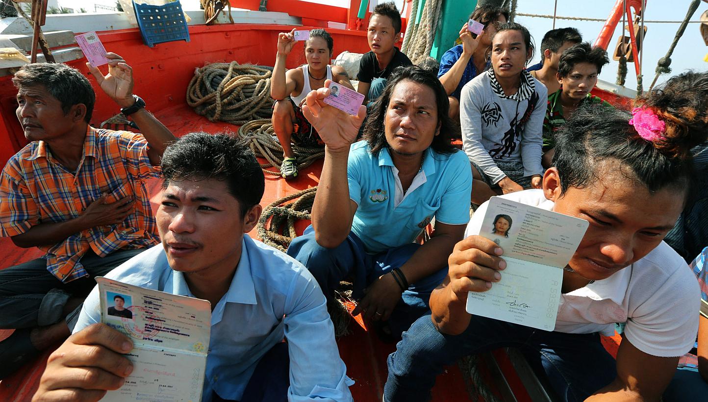 Migrant workers show their migrant worker cards as Thai authorities inspect a fishing boat in Mae Klong district, Samut Songkhram province, Thailand, on May 7, 2015. -- PHOTO: EPA
