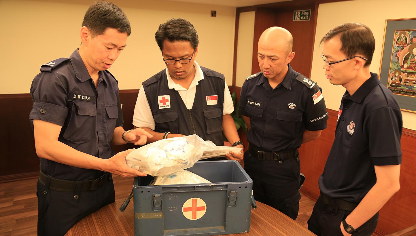 The Singapore Red Cross receiving boxes of medical supplies from the Home Team contingent. Present is (from left) Major (NS) Alex Kuan, Mr Khairulnizam, Lieutenant-Colonel Alvin Tan and Assistant Commissioner Lian Ghim Hua. -- PHOTO: MINISTRY OF HOME