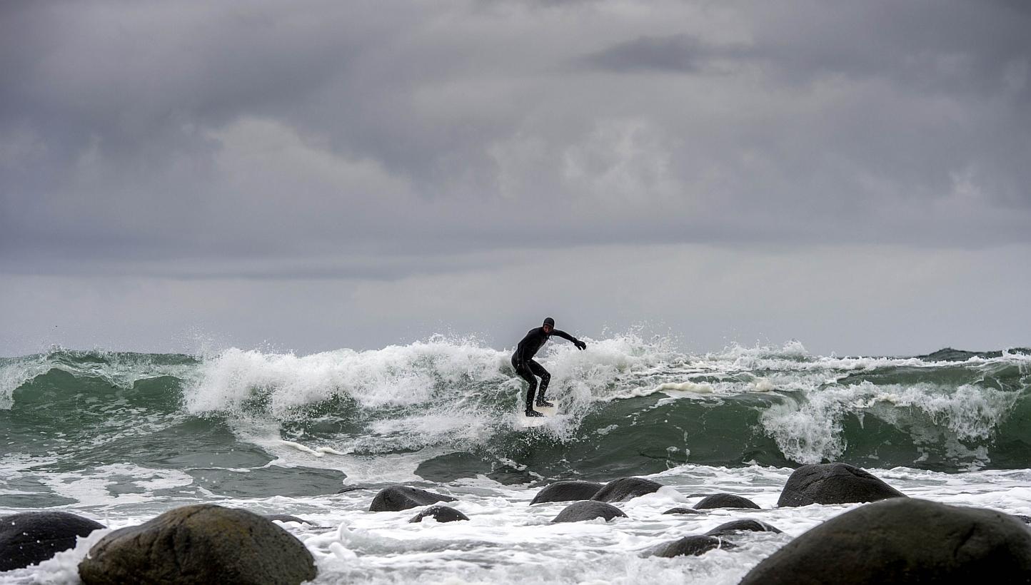 A Swedish tourist surfs last month in Unstad beach in the Lofoten Islands within the Arctic Circle, where carbon dioxide levels rose to record highs in 2012. -- PHOTO: AFP